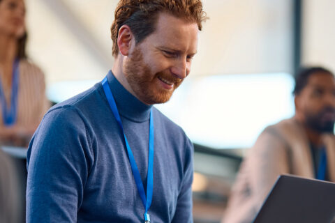ACTICO Header Happy entrepreneur working on laptop while participation in business education event in conference hall.